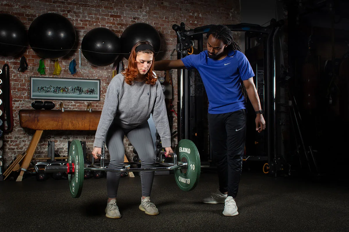 Atleet voert onder begeleiding een trap bar deadlift uit